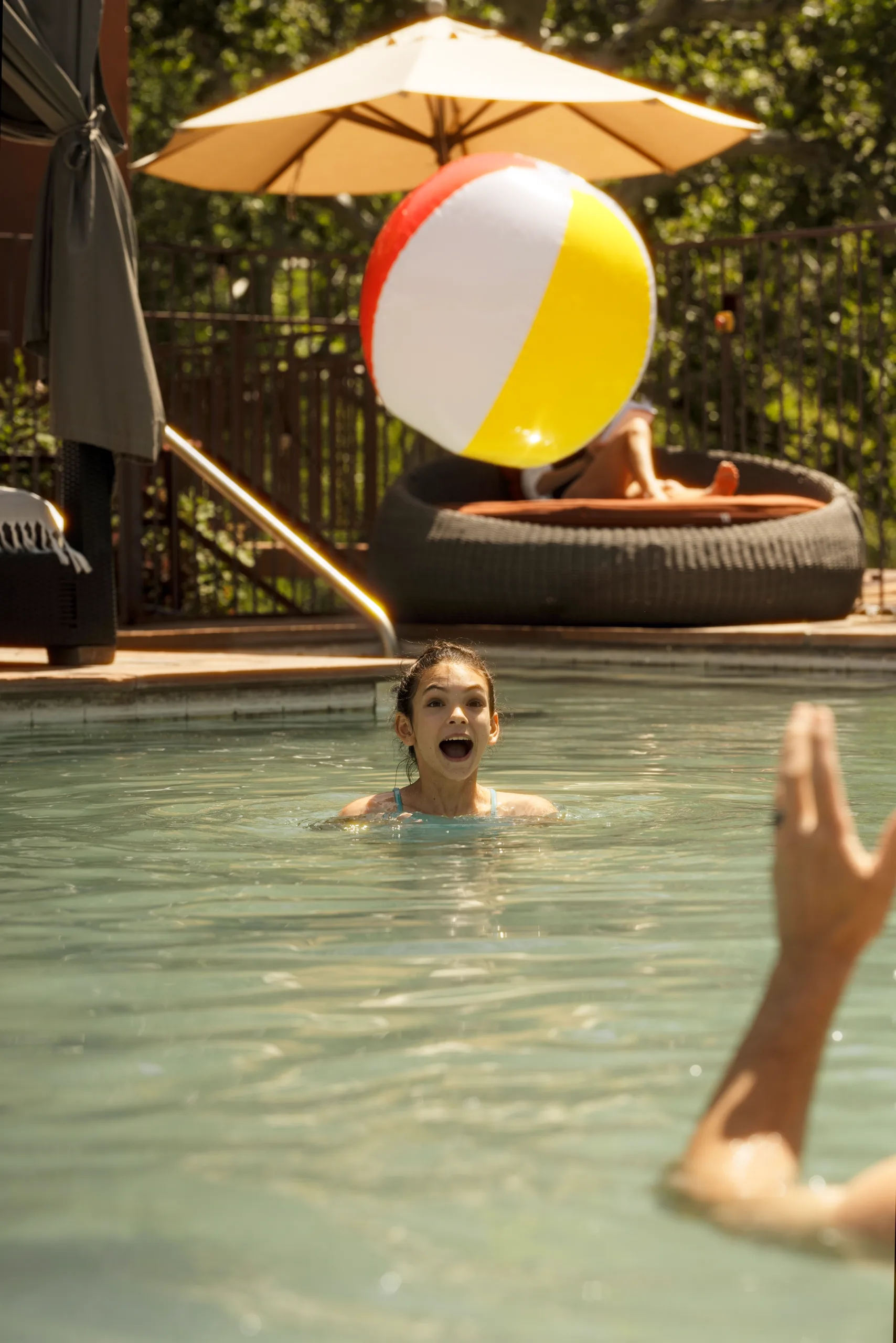 A girl reaches for a beach ball in the pool