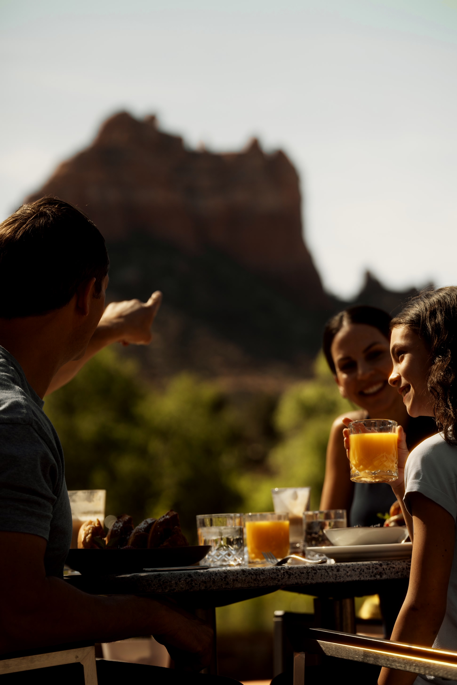 A family shares drinks on a terrace facing the red rocks