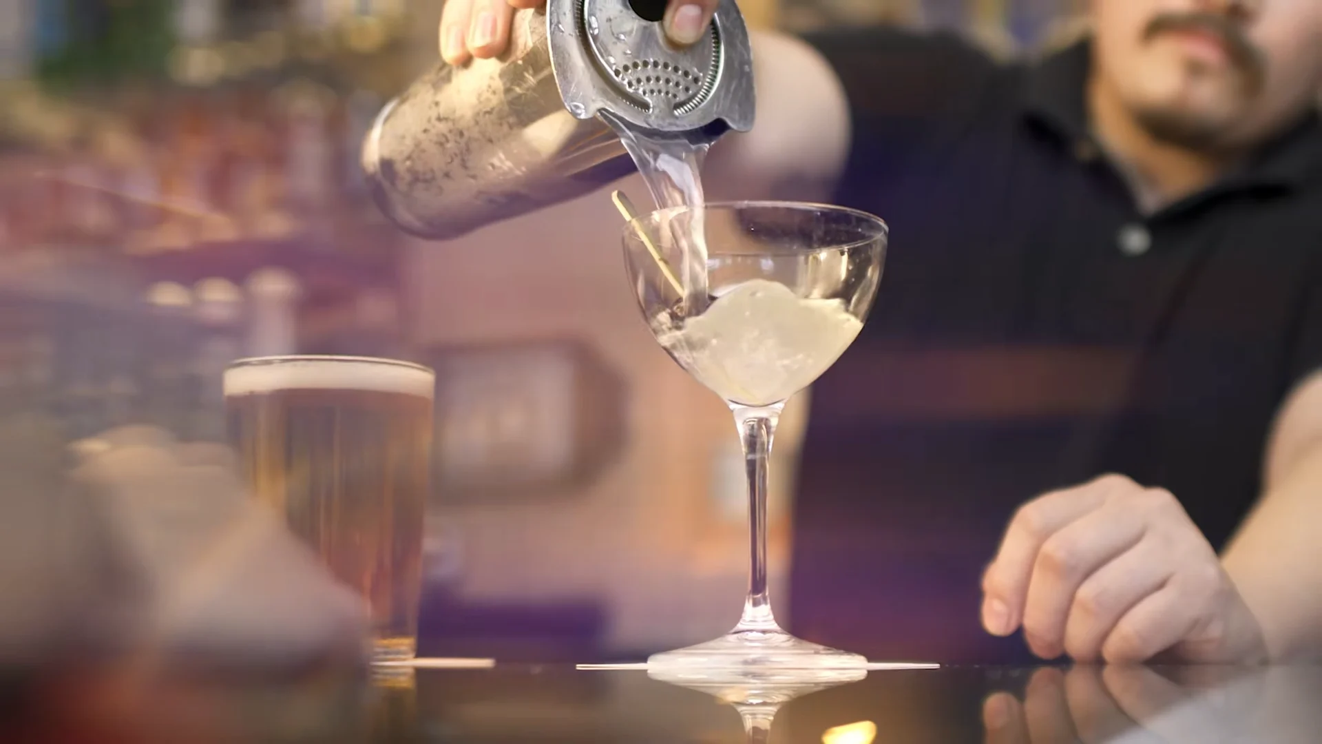 A bartender pours a martini