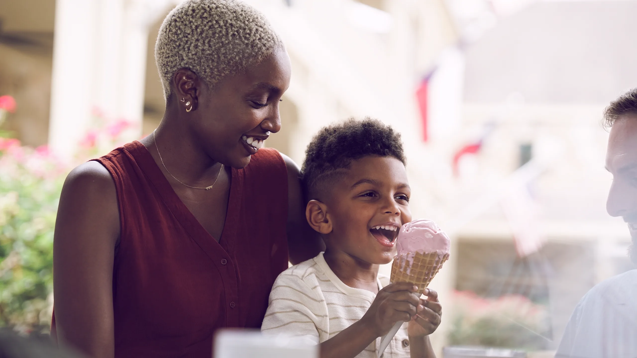 A boy laughs over an ice cream cone with his mother