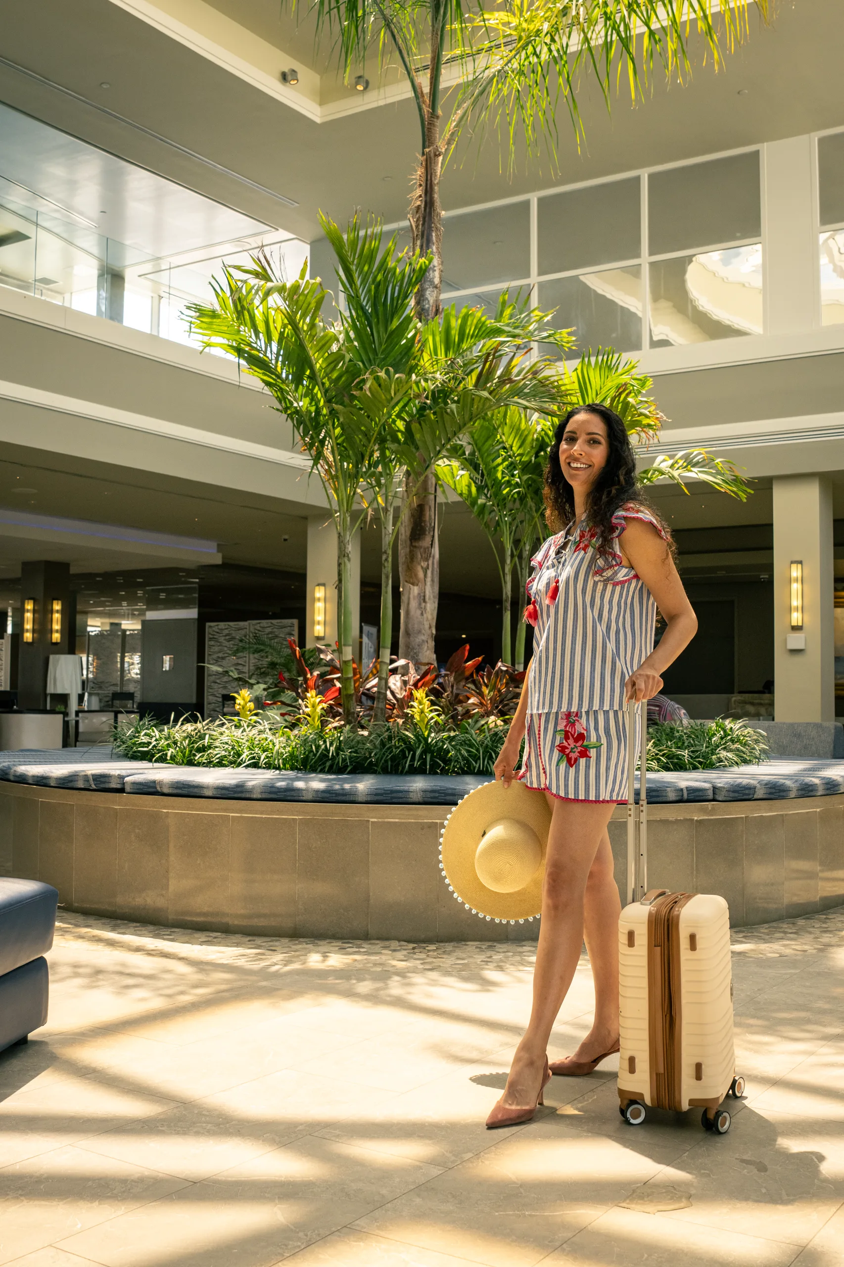 A guest arrives with her suitcase in the palm-filled atrium