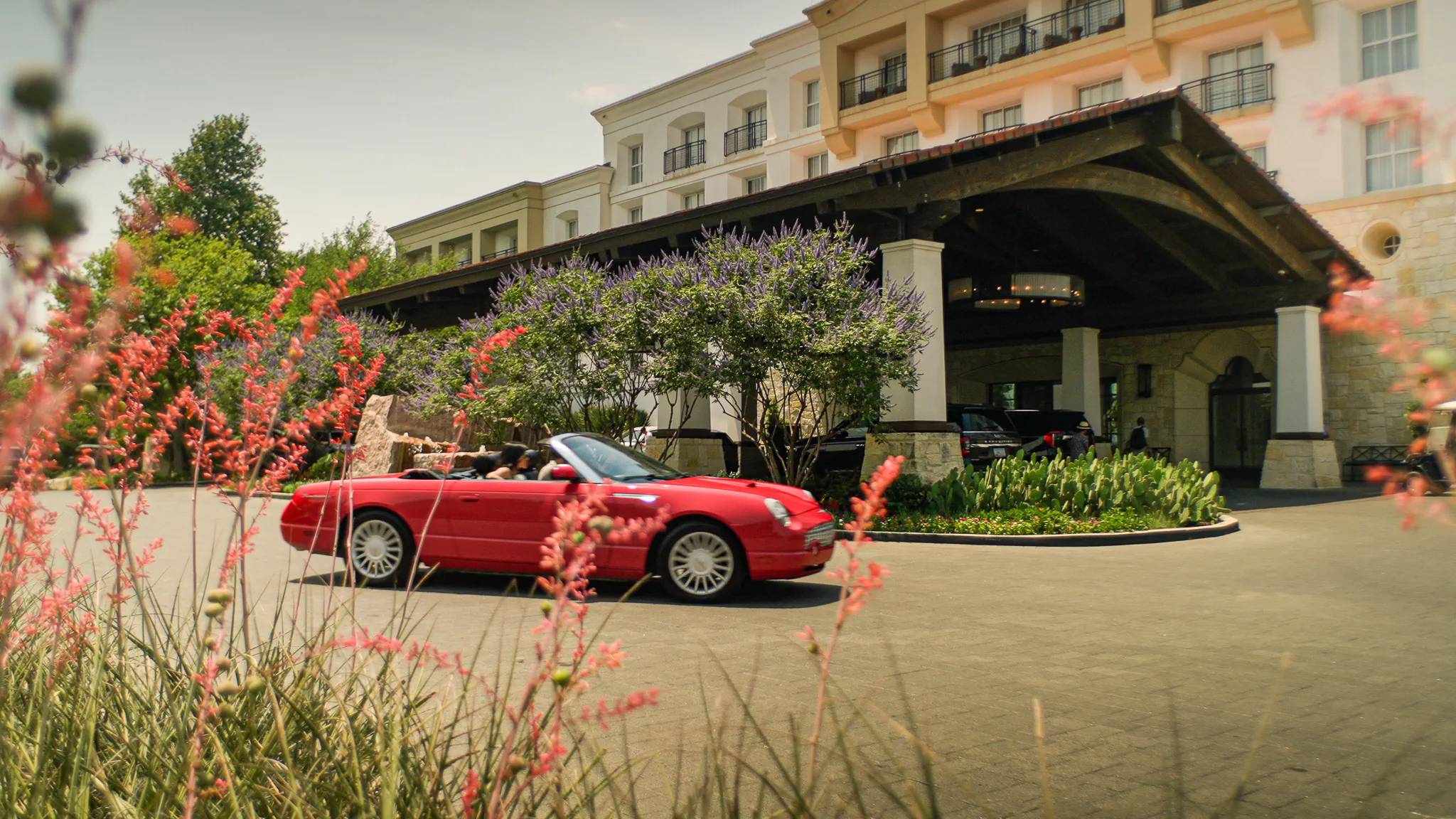A red convertible arrives at the porte-cochère