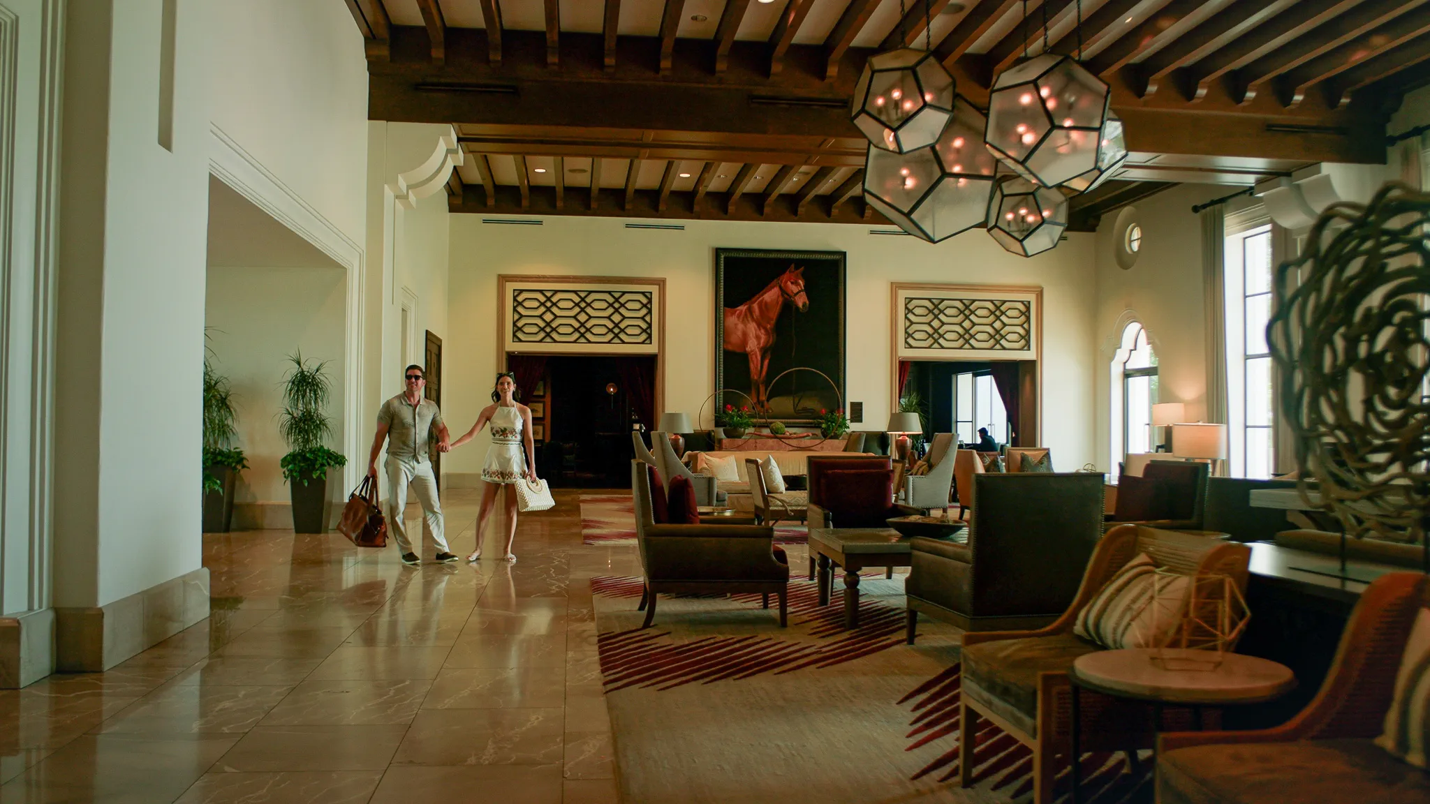 A couple walks through the lobby living room with weekend bags