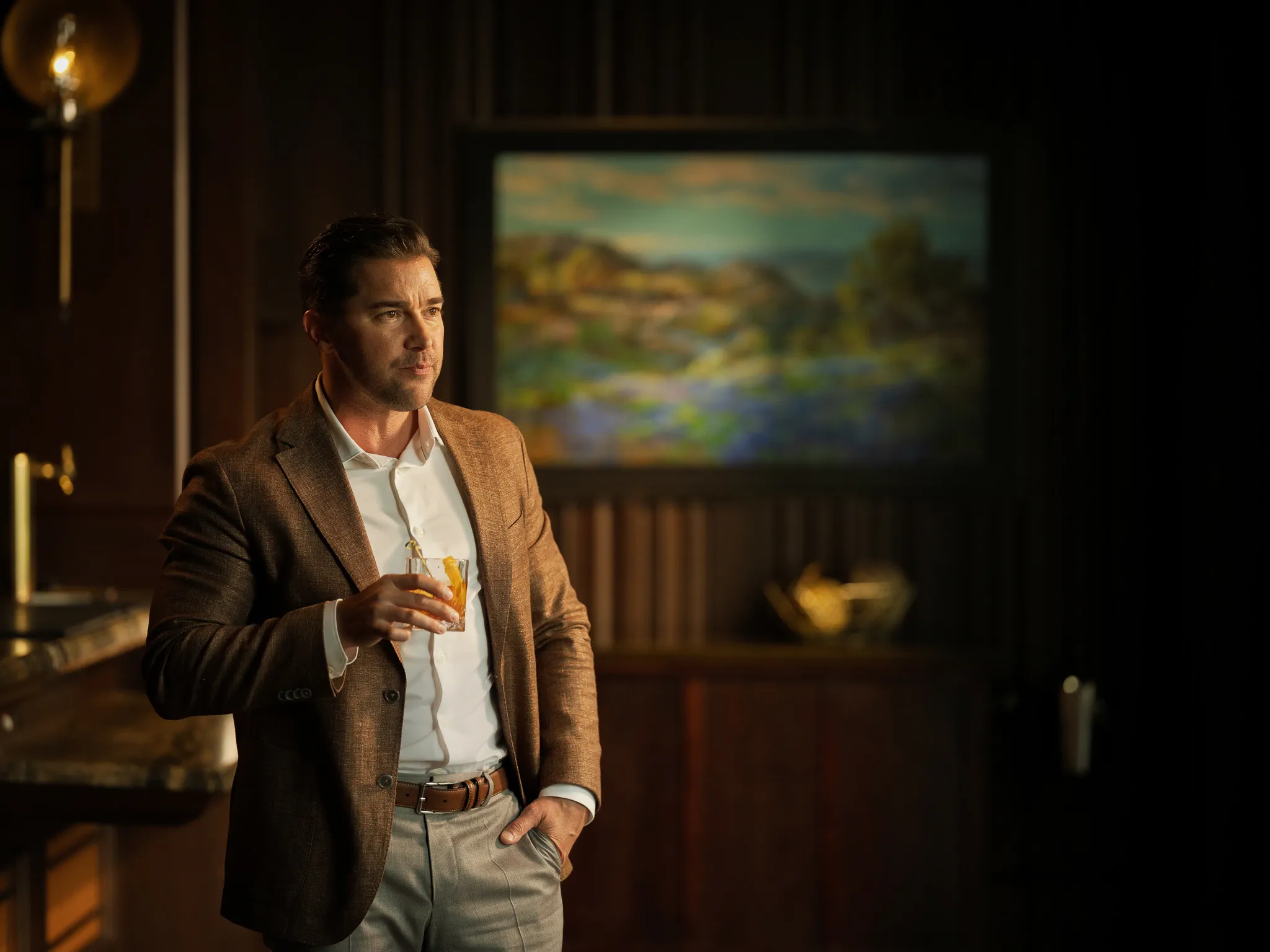 A guest holds a nightcap beside a Hill Country painting
