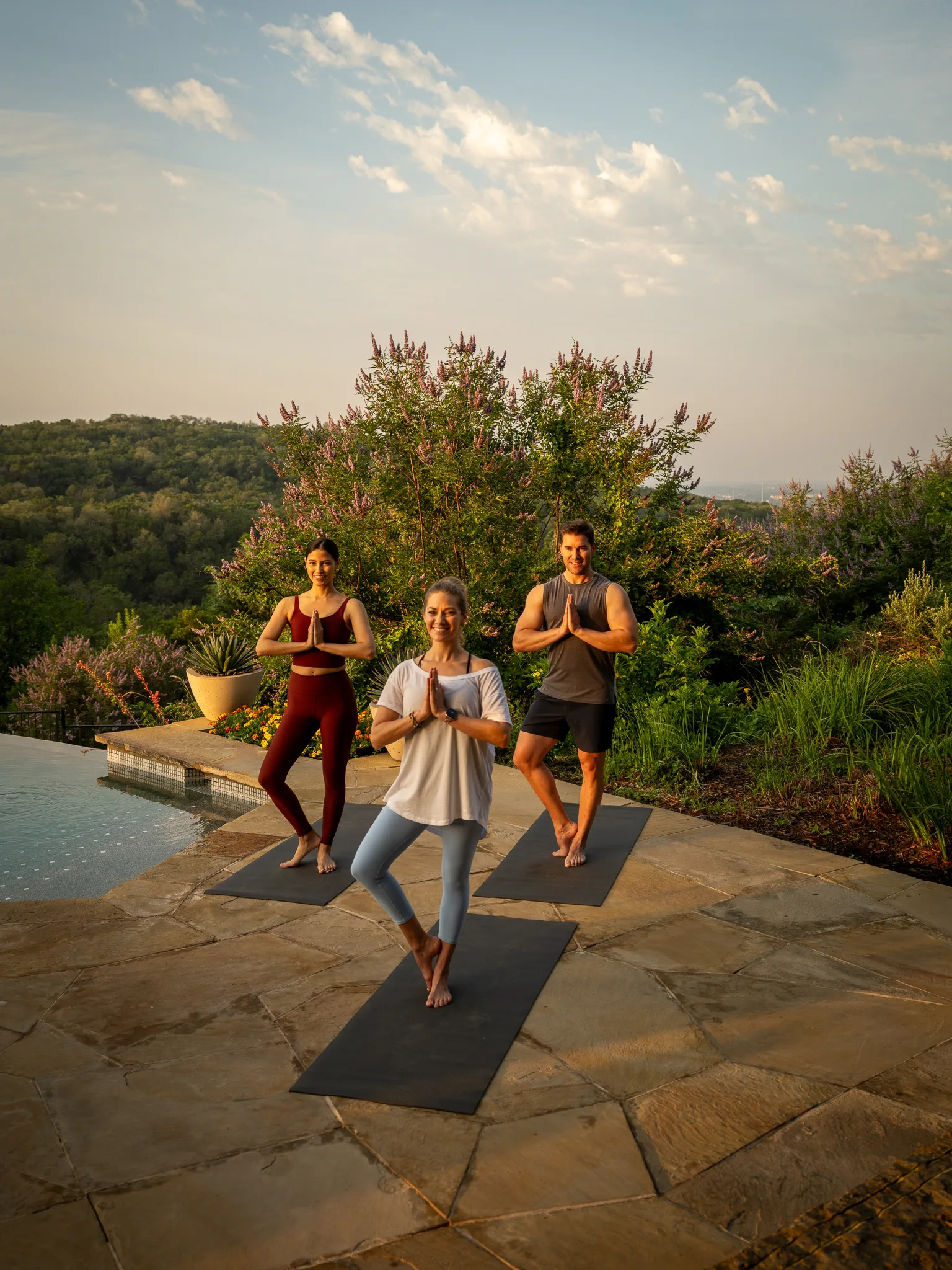 Three guests in a sunrise yoga class beside the spa pool